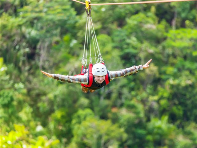 Men enjoying zip-line flying over the forest
